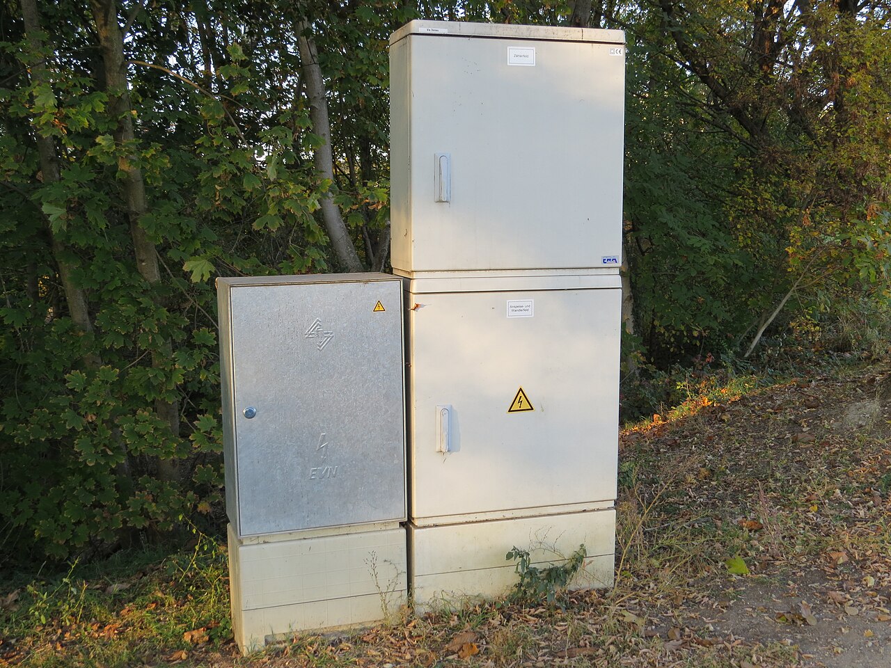 Technician clamping non-intrusive split-core current transformers around 3-phase feeder cables inside a distribution board without cutting factory power